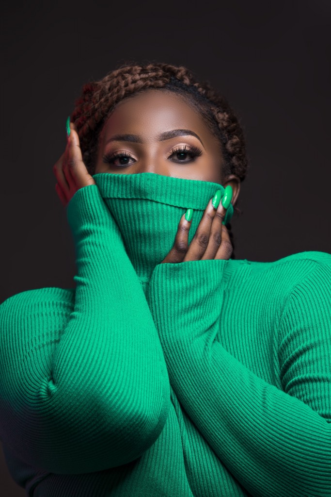Picutre of a fully made up woman in a green turtleneck to illustrate how lipstick companies can remain relevant during the coronavirus